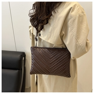 Close-up of a dark brown quilted underarm bag featuring metallic rivet studs and V-pattern