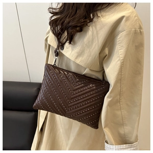 Detail of dark brown leather crossbody bag with V-quilted pattern and silver stud accents
