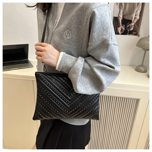Detail of black quilted shoulder bag with silver studs and elegant chevron texture