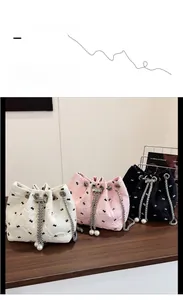 Bow embroidered bucket bags in white pink and black with pearl drawstring chains