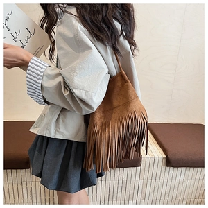 Detail of vintage brown suede shoulder bag featuring long fringe tassels and sleek strap