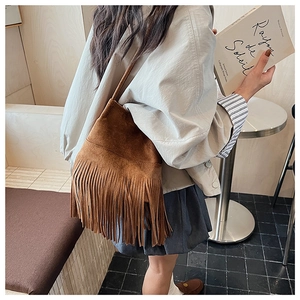 Close-up of retro brown suede bucket bag with long tassels and thin leather strap