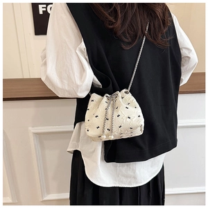 Detailed shot of white bucket bag with floral patterns, chain strap, and pearl charms