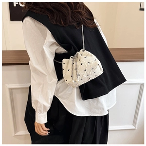 Close-up of cream bucket bag with black bow print and pearl drawstring details