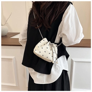Close-up of bucket bag with black bow patterns and elegant pearl chain strap detail