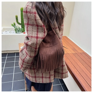 Close-up of deep brown suede shoulder bag featuring long fringe tassels in bohemian style