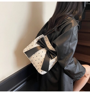 Detail of white embossed tote bag with black bow patterns and leather ribbon accent