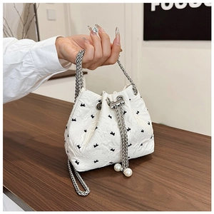 Detail of white jacquard bucket bag with black bows, silver chain and pearl charms