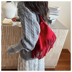 Detail of red tassel shoulder bag in suede finish with bohemian fringe and modern design