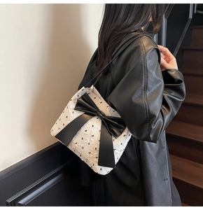Detail of white tote bag with embossed texture and a large decorative black leather bow