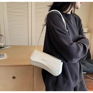 Detail of white rectangle shoulder bag with gold text and knotted rope strap