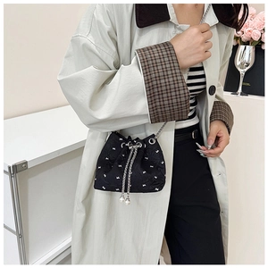Detail of black bow embroidery bucket bag with silver chain and pearl drawstrings