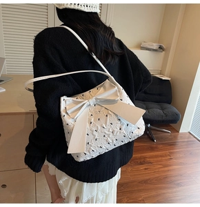 Close-up of white tote bag with quilted texture, animal pattern, and large leather bow
