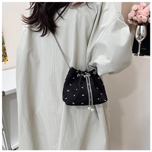 Close-up of black bucket bag with pearl tassels and white embroidered bow patterns
