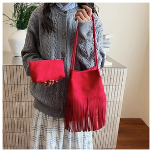 Detalle de un bolso de hombro rojo con flecos y neceser a juego con textura de gamuza