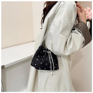 Detail of black drawstring bucket bag with white bow pattern and pearl tassels