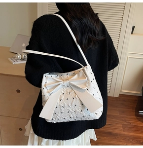 Detail of white textured fabric shoulder bag with large bow and bunny embroidery
