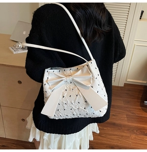 Detail of white bow shoulder bag with animal print on a textured quilted fabric