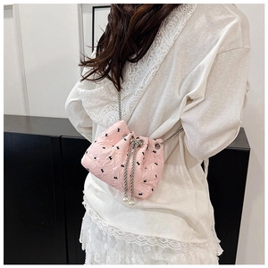 Pink pleated drawstring bucket bag with black bows and pearl accents on a model