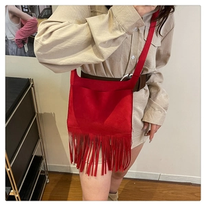 Détail du sac bandoulière rouge en daim avec longues franges et fines lanières