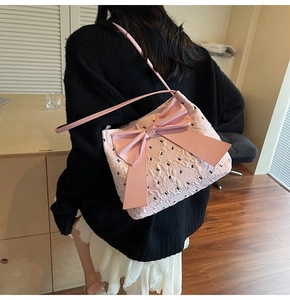 Detail of pink bow shoulder bag with embossed patterns and satin ribbon decoration