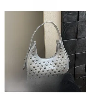 Dettaglio della borsa metallizzata argento con borchie punk e texture liscia