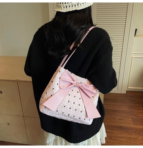 Detail of pink shoulder bag featuring a large bow and black bunny embroidery motifs