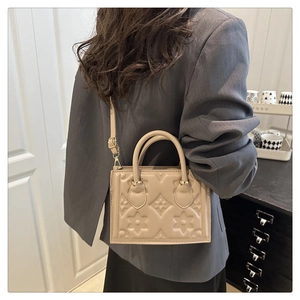 Detail of beige embossed tote bag with star pattern and adjustable shoulder strap