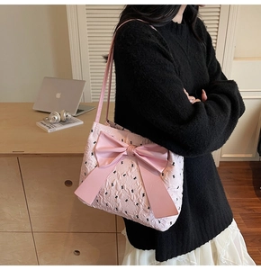 Pink bow shoulder bag with floral pattern shown on a model in a cozy indoor setting