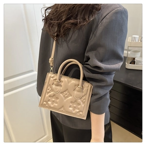 Detail of floral embossed texture and gold metal hardware on chic beige crossbody handbag