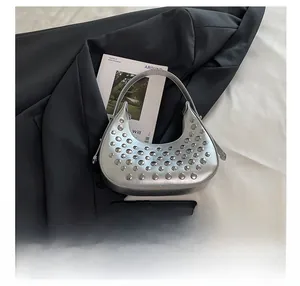 Confronto dimensioni borsa a mano in pelle argentata con borchie e smartphone