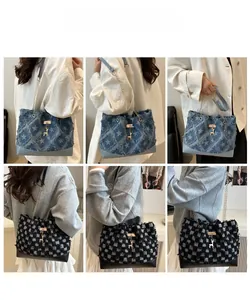 Detail of denim tote bag with star pattern, frayed edges, and golden deer charm