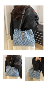 Detail of blue denim checkerboard bucket bag with gold chain and deer pendant charm
