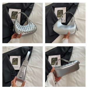 Dettaglio macro della borsa a mezzaluna argento con borchie punk e pelle metallizzata