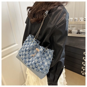 Detail of blue plaid denim patchwork tote bag with fringed edges and gold deer charm