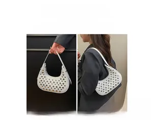 Dettaglio borsa a mezzaluna bianca con borchie argentate e tracolla versatile