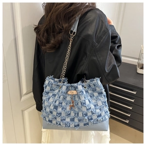 Detail of blue denim patchwork bucket bag with golden chain strap and deer charm