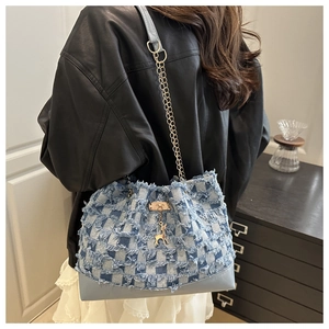 Détail du sac en denim à damier bleu avec chaîne dorée et pendentif cerf