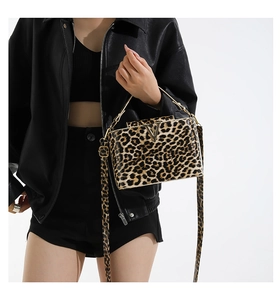 Close-up of leopard print crossbody bag with golden V logo on chic black leather outfit