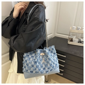 Détail du sac cabas en denim à damier avec bords effilochés et pendentif cerf doré