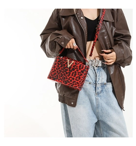 Detail of red leopard print handbag with gold V-buckle decoration and shoulder strap