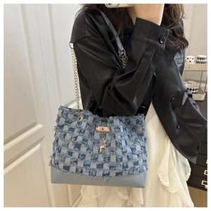 Detail of denim patchwork tote bag with frayed edges and golden deer pendant