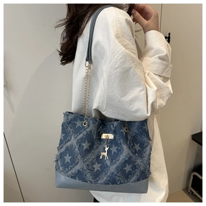 Detail of blue denim tote bag with star print, metal chain, and deer charm accessory