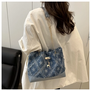 Detail of blue denim bucket bag with white star pattern and golden deer pendant decoration