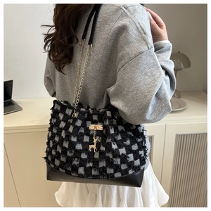 Détail du sac cabas à carreaux avec breloque cerf dorée et texture tweed à franges