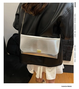 Détail de la pochette argentée avec fermoir rectangulaire doré et fine bandoulière