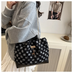 Close-up of black and white checkered tweed bucket bag with golden deer charm and chain
