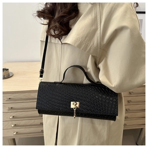 Close-up of a woven black baguette bag featuring gold hardware worn with a beige coat