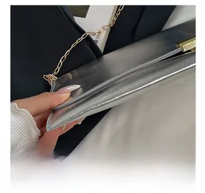 Détail du sac bandoulière argenté avec chaîne dorée et texture métallique chic