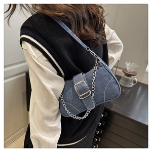 Dettaglio borsa baguette in denim blu scuro con catena argento e fibbia sulla spalla